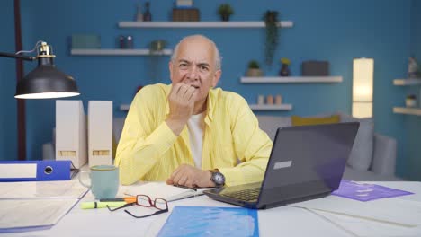 Home-office-worker-old-man-biting-his-nails-looking-at-camera.